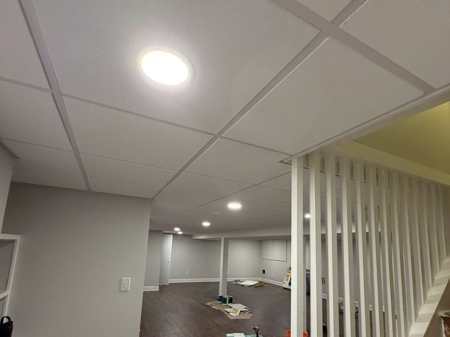Finished basement with stair feature and white suspended ceiling
